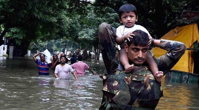 Chennai: Army personnel carry children on their shoulders as they wade through flood waters in rain-hit Chennai on Thursday. PTI Photo(PTI12_3_2015_000387B)